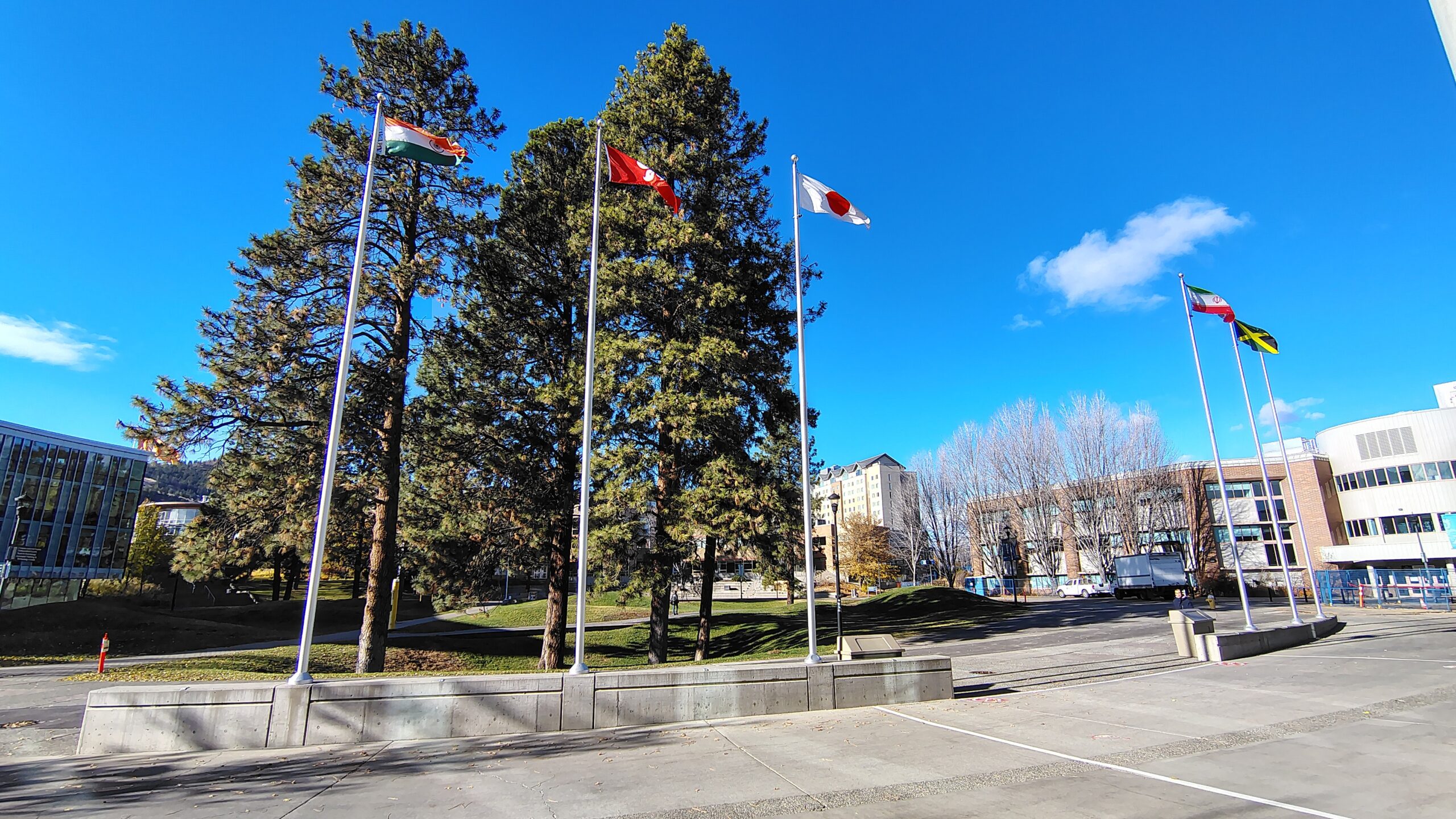 The international student flag plaza at Thompson Rivers University, empty. The flags name the countries whose students fund this institution.